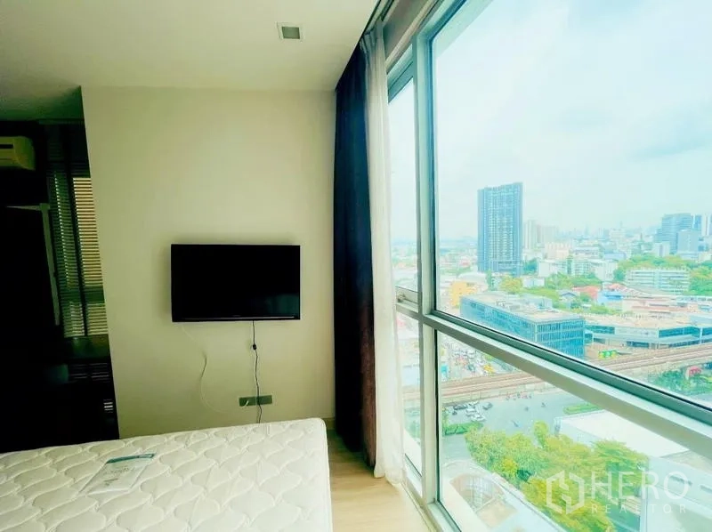 คอนโด ให้เช่า - ห้องนอนติดทีวีผนังและหน้าต่างกระจกสูงมองเห็นวิวเมืองกรุงเทพฯ