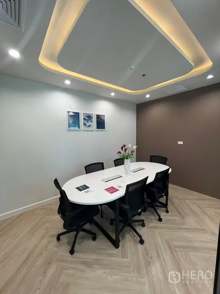 Office Space for rent - Boardroom with oval table for six under recessed ceiling lights.