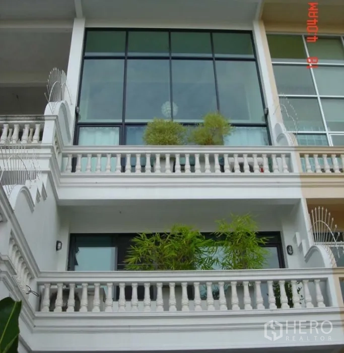 联排别墅 出售在Phra Khanong, Bangkok - 多层联排别墅外立面，落地玻璃与双阳台，摆放竹植，靠近BTS Punnawithi