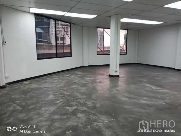 办公空间 出租在Bang Na, Bangkok - 大开间办公室，水泥地面、中央立柱与临街窗户。