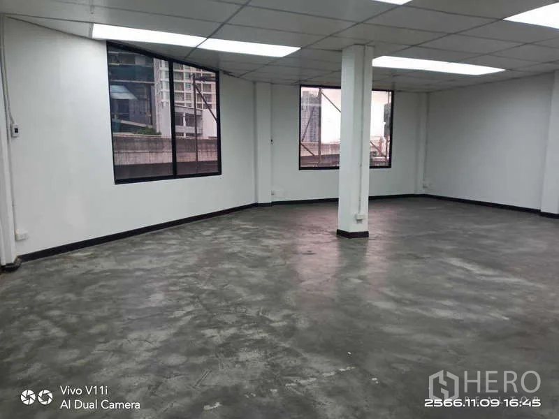 办公空间 出租在Bang Na, Bangkok - 大开间办公室，水泥地面、中央立柱与临街窗户。