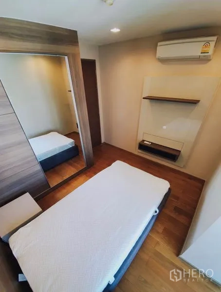 Condominium for rent in Bang Rak, Bangkok - Compact second bedroom with single bed, mirrored wardrobe and wood floors.