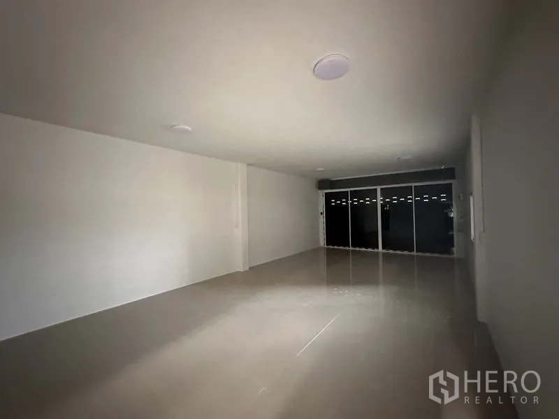 Warehouse for rent in Sai Noi, Nonthaburi - Empty office space with sliding glass doors and tiled floors inside the warehouse.