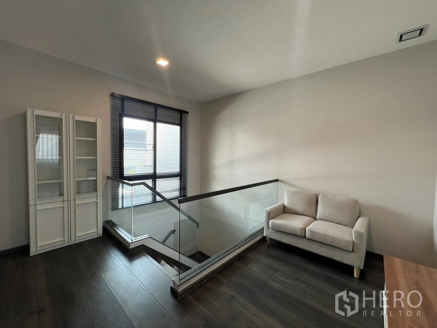 Detached House for rent in Bang Phli, Samut Prakan - Upper landing with glass balustrade, window and small sofa.