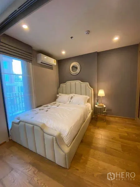 公寓 出售在Ratchathewi, Bangkok - 卧室另一角度，软包床头、暖色灯光与推拉阳台门。