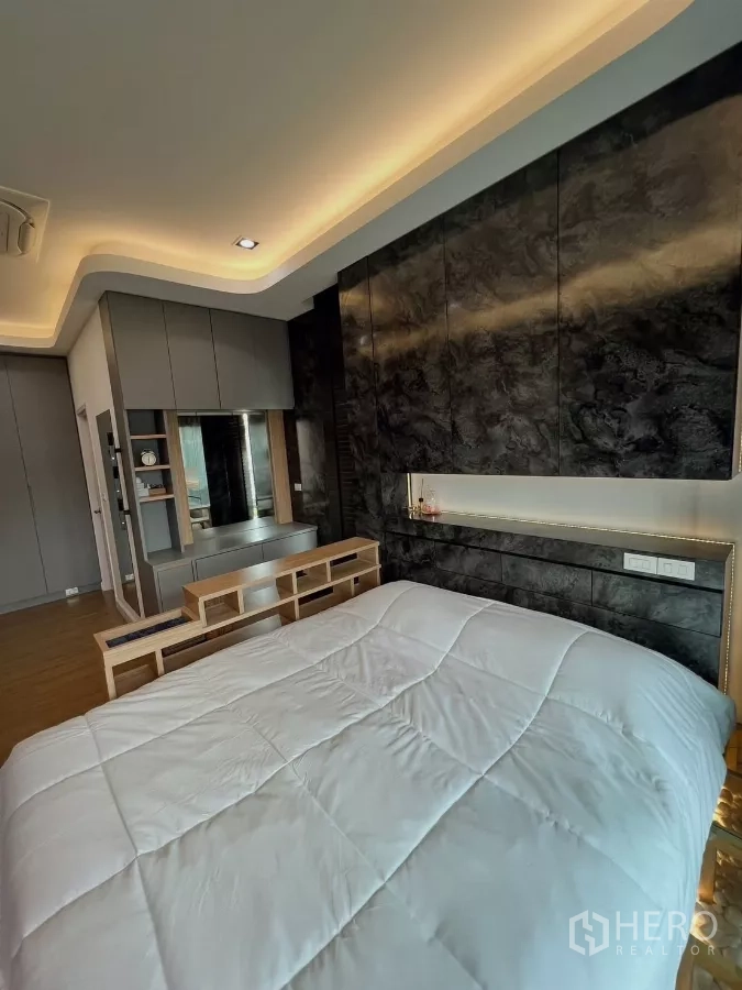 Detached House for rent or sale in Khlong Luang, Pathum Thani - Master bedroom platform bed with underlighting and textured feature wall.