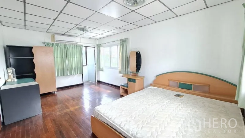 独立式住宅 出租在Lat Phrao, Bangkok - 主卧面积大，木地板、绿色窗帘与成套家具。