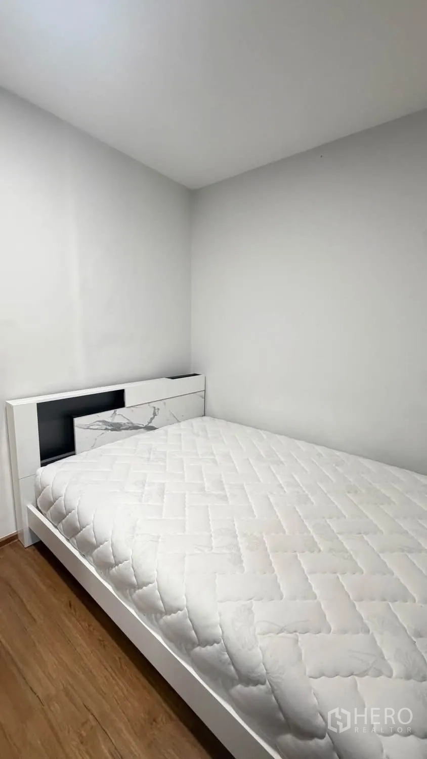 Townhouse for rent in Bang Phli, Samut Prakan - Compact bedroom with a white bed frame and wood-look flooring.