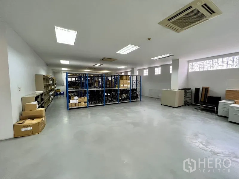 Office Space for rent in Bueng Kum, Bangkok - Spacious open-plan storage or office area with blue metal shelving, bright fluorescent lighting, and polished concrete floor.