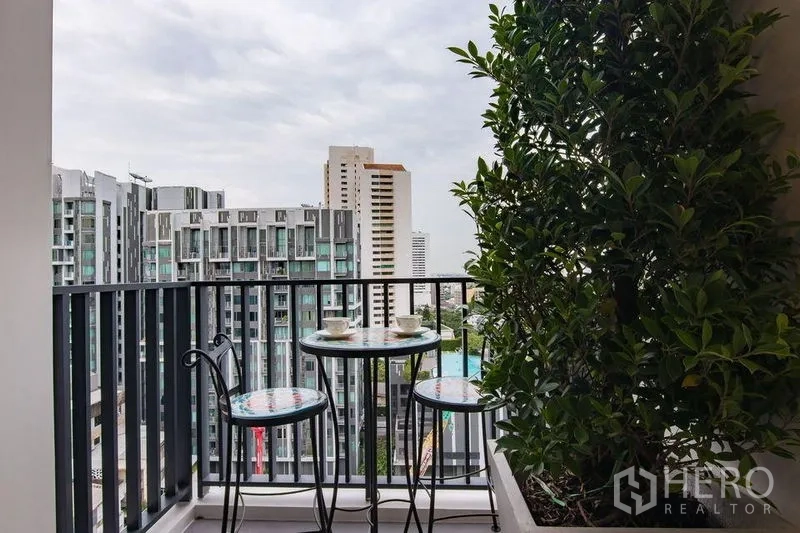 Condominium for sale in Watthana, Bangkok - Private balcony with bistro table, planter and open skyline views of the city.