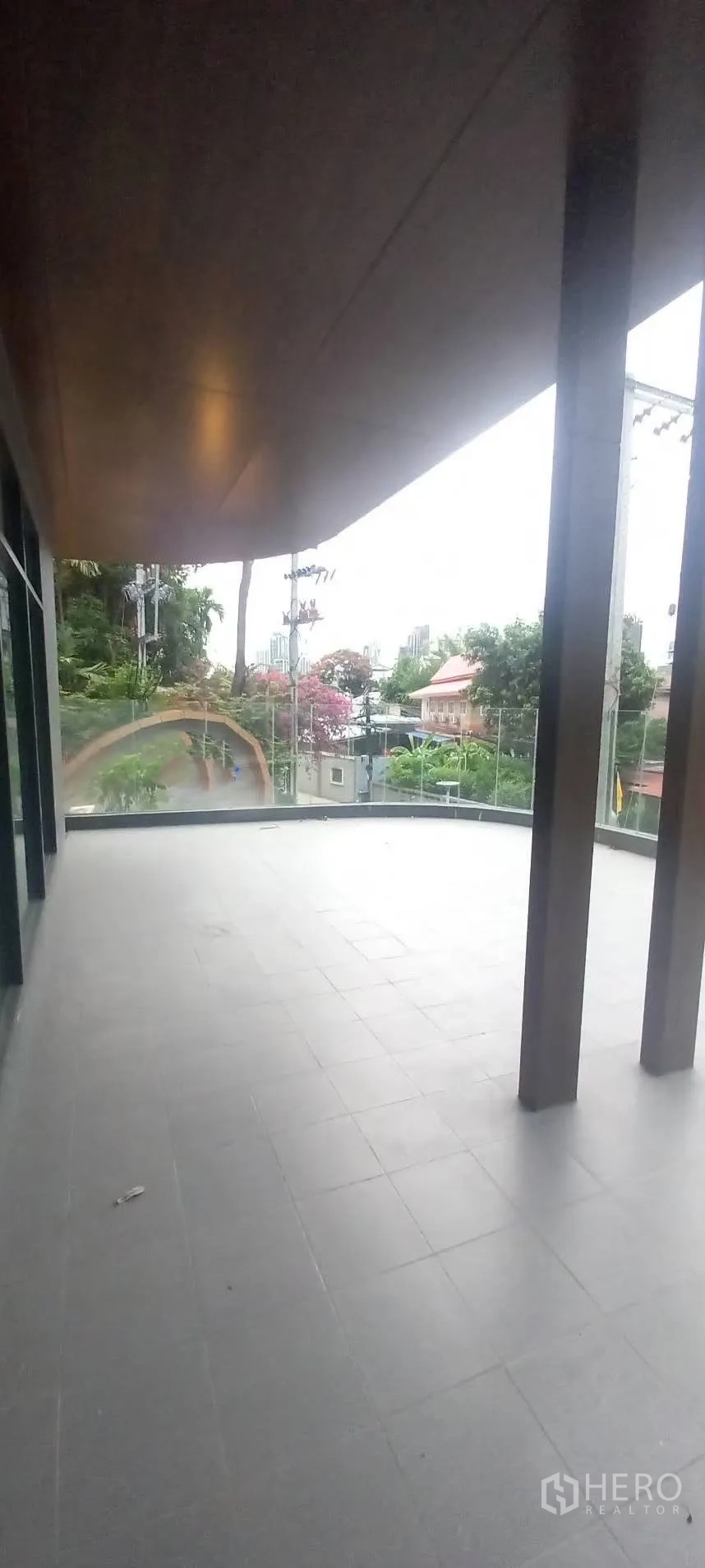 Retail Space for rent in Watthana, Bangkok - Spacious upper terrace with tiled flooring and glass balustrade overlooking greenery and city glimpses.
