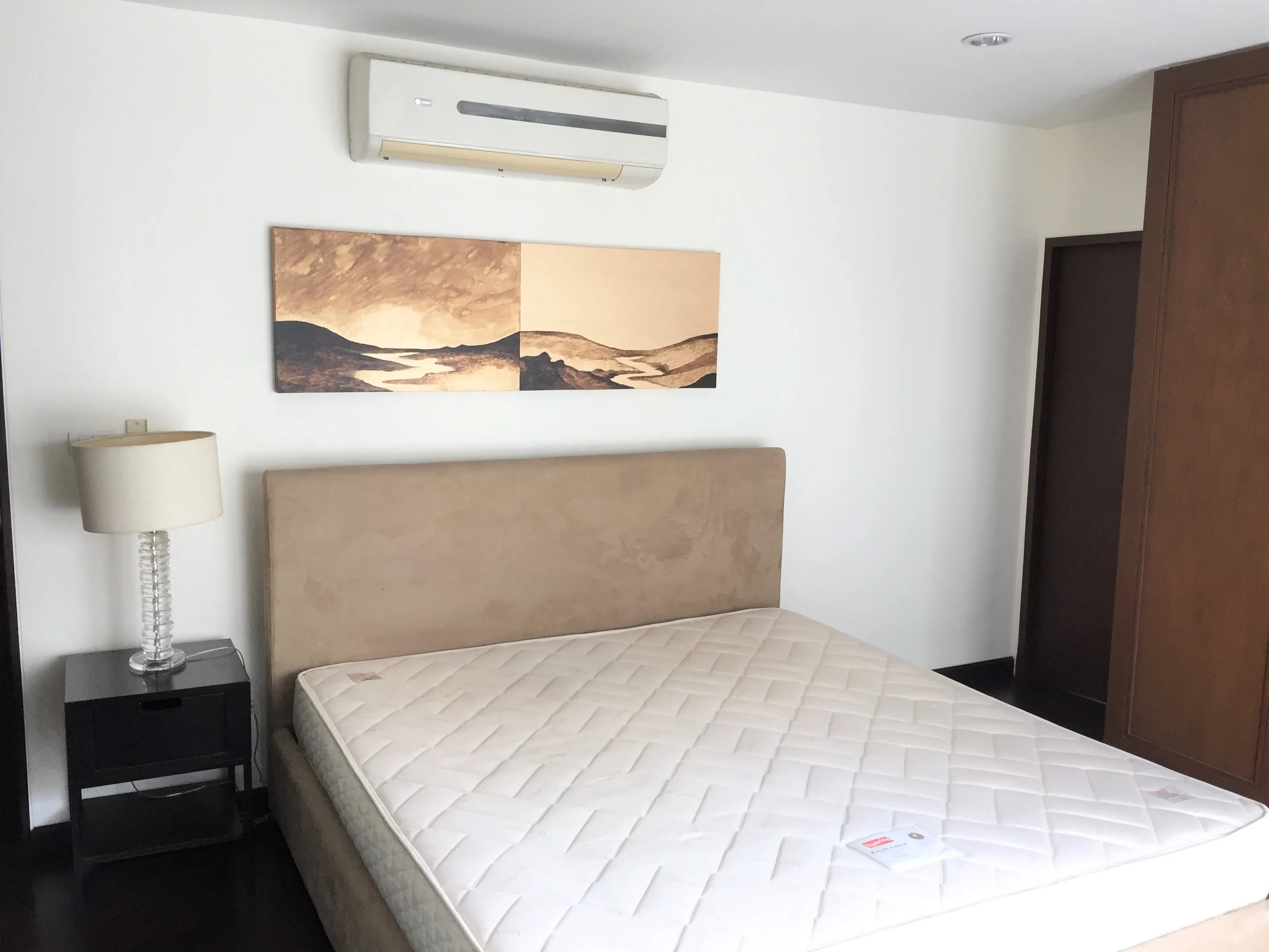 Condominium for rent in Sathon, Bangkok - Second bedroom with upholstered headboard, bedside lamp, air conditioner and wardrobe.