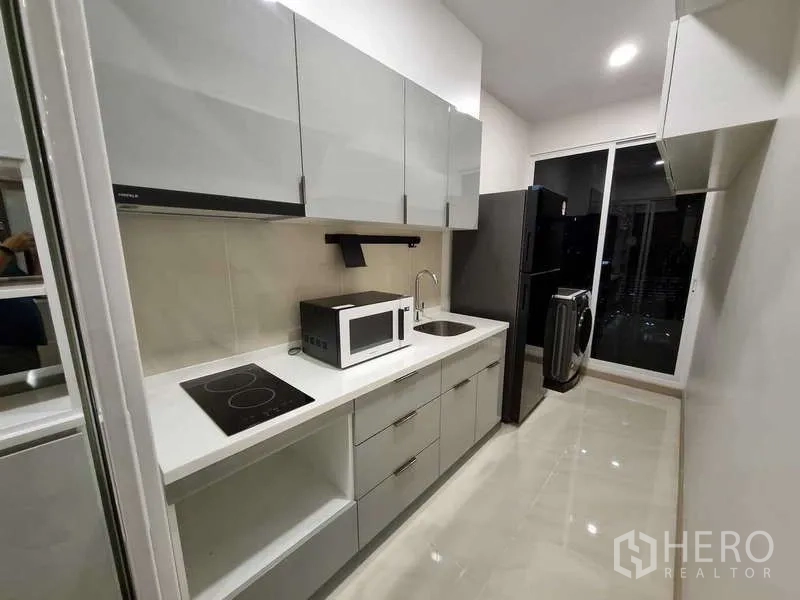 Condominium for rent - Fully equipped kitchen with induction hob, microwave, sink and tall storage cabinets.