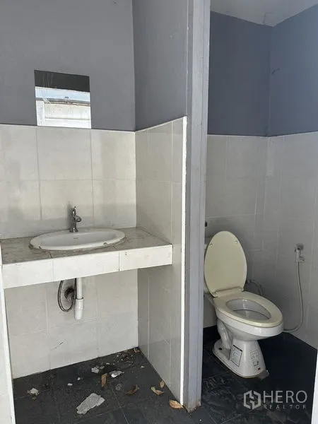 Warehouse for rent in Lat Phrao, Bangkok - Simple restroom with toilet, hand sprayer and sink with tiled walls.
