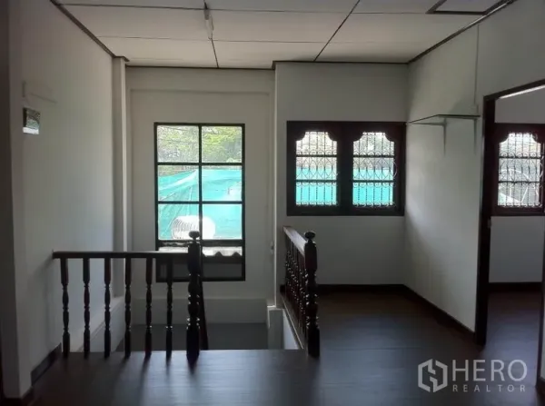 Warehouse for rent in Lam Luk Ka, Pathum Thani - Stair landing with a wooden balustrade and windows fitted with security bars.