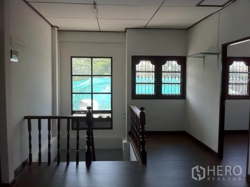 Warehouse for rent in Lam Luk Ka, Pathum Thani - Stair landing with a wooden balustrade and windows fitted with security bars.