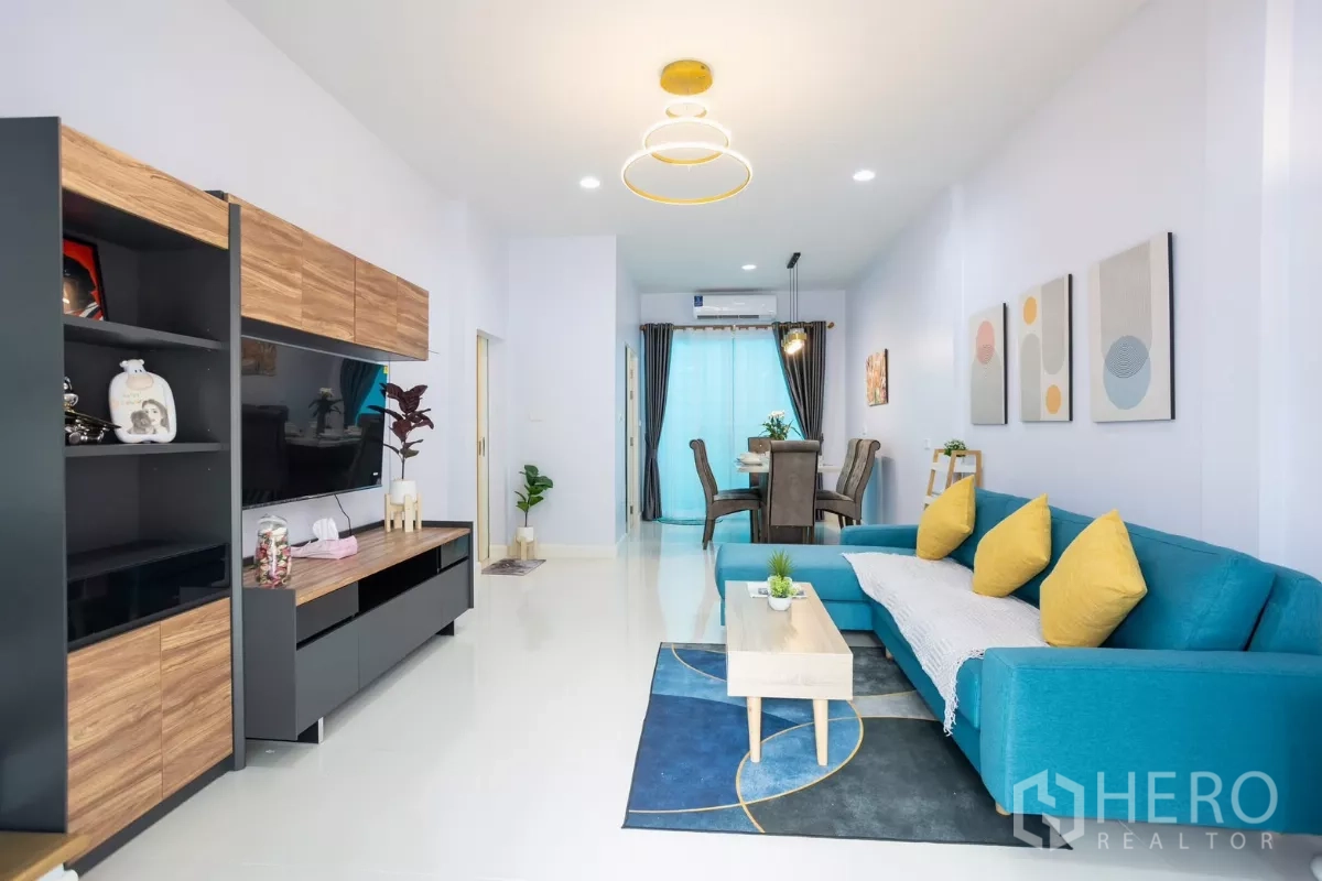 Townhouse for rent - Bright living room with teal L-shaped sofa, coffee table and wood media cabinet