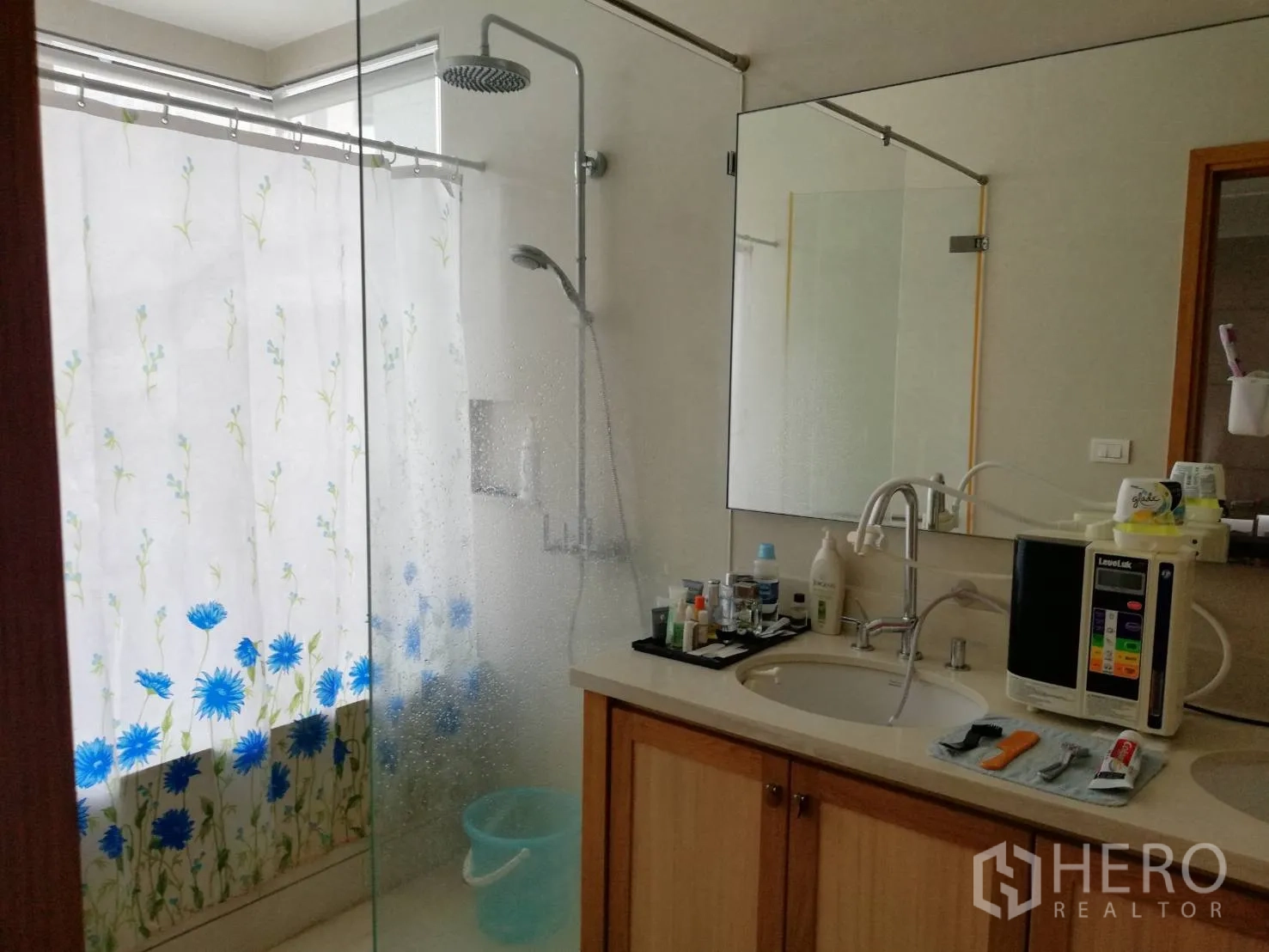 Condominium for sale in Khlong Toei, Bangkok - Bathroom with rain shower, glass partition and long vanity with mirror.