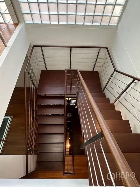 Townhouse for sale in Yan Nawa, Bangkok - Top-down view of staircase with wooden treads and metal railings under a skylight.