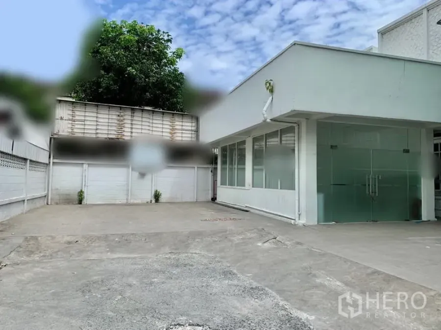 零售空间 出租在Khlong Toei, Bangkok - 白色单层商业建筑，玻璃双开门，前方混凝土空地可停车与装卸。