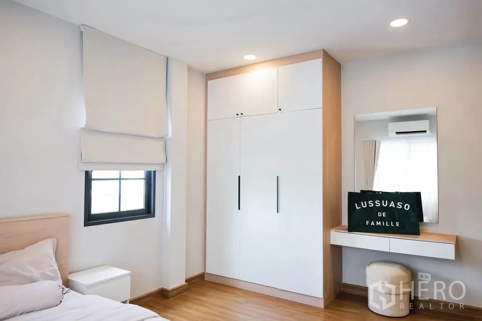 บ้านเดี่ยว for sale in Bang Phli, Samut Prakan - ห้องนอนสว่างมีตู้เสื้อผ้าสีขาว โต๊ะเครื่องแป้ง และหน้าต่างพร้อมมู่ลี่.