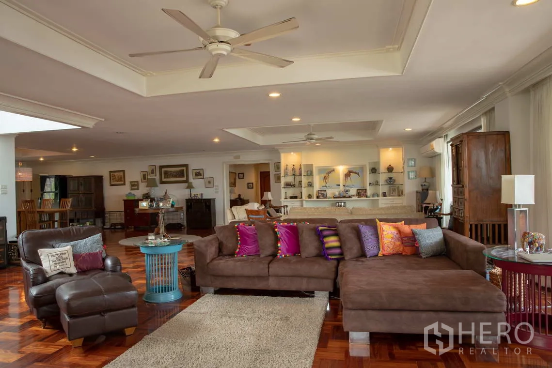 อพาร์ทเมนท์ for rent in Khlong Toei, Bangkok - ห้องนั่งเล่นกว้างพร้อมโซฟาตัวยาว พัดลมเพดาน และชั้นบิวท์อิน.