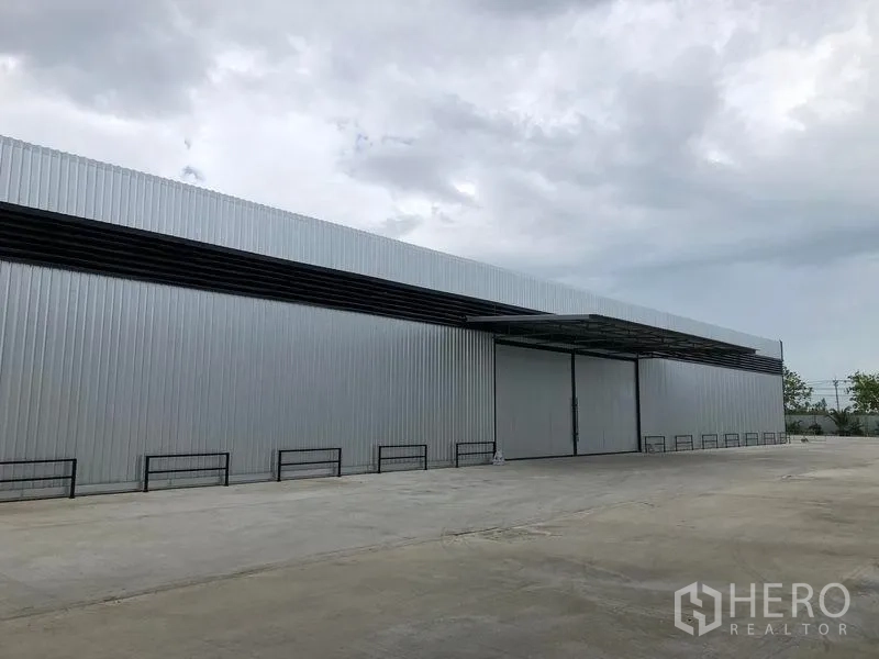 货栈 出租在Pathum Thani - 金属板仓库侧立面，带雨棚的装卸区与宽敞车道。