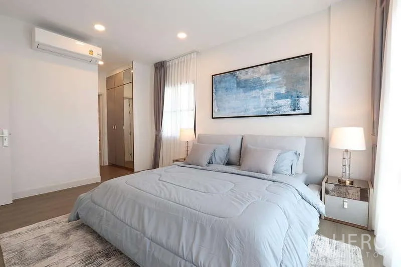 Detached House for rent in Saphan Sung, Bangkok - Light-filled bedroom with gray bedding, bedside lamps and built-in wardrobe area.
