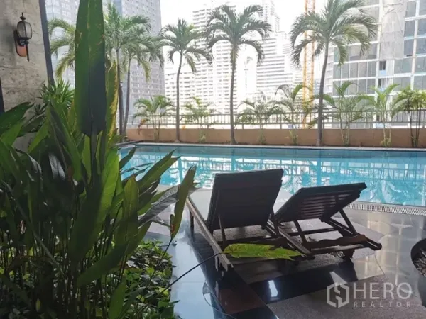 公寓 出租在Watthana, Bangkok - 泳池甲板配躺椅与热带植物，眺望曼谷天际线。