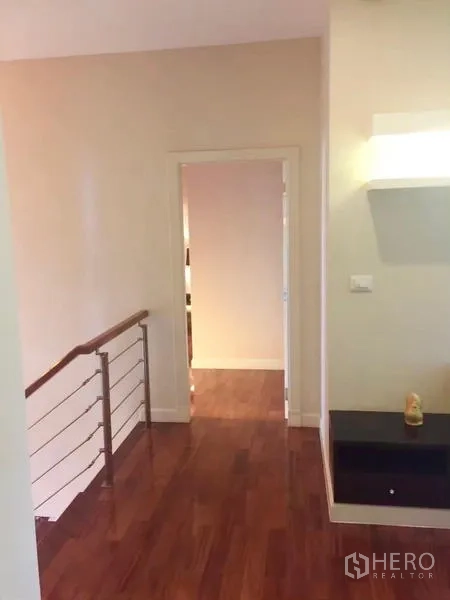 Detached House for sale in Lat Krabang, Bangkok - Upper hallway with wooden flooring, railing and a small wall shelf.