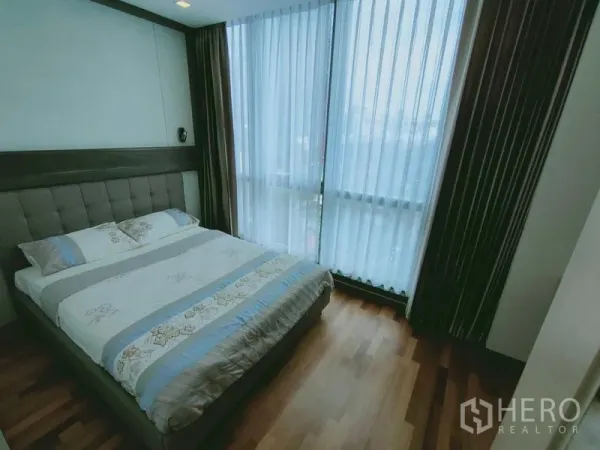 公寓 出租在Ratchathewi, Bangkok - 主卧配软包床、木地板与转角落地窗及窗帘。