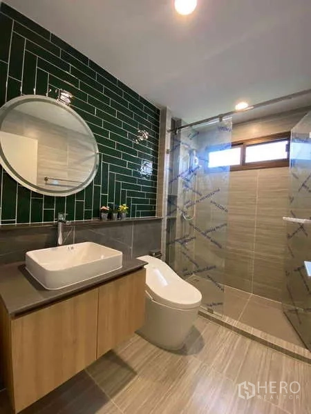 Detached House for rent in Bang Kapi, Bangkok - Modern bathroom with green feature tiles, vanity and glass-enclosed shower.