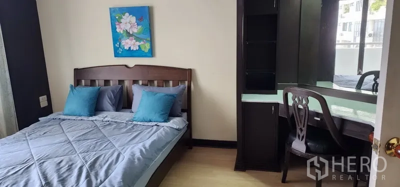 公寓 出售在Watthana, Bangkok - 次卧配蓝色床品与木床，带内置梳妆台与镜面。