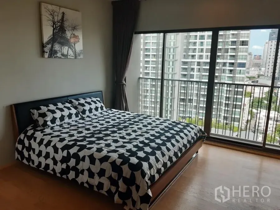 公寓 出租在Bangkok - 卧室转角的整面落地窗与阳台栏杆，俯瞰素坤逸天际线。