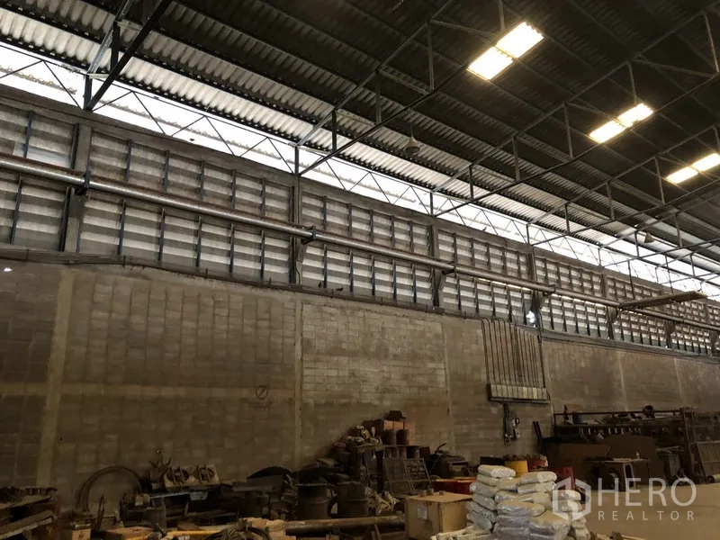Factory for rent in Bang Bua Thong, Nonthaburi - Ventilated block wall with high louvered windows above storage racks inside the factory.