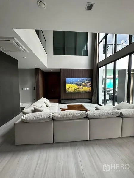 Detached House for rent in Saphan Sung, Bangkok - Living area with high ceilings and feature wall-mounted TV.