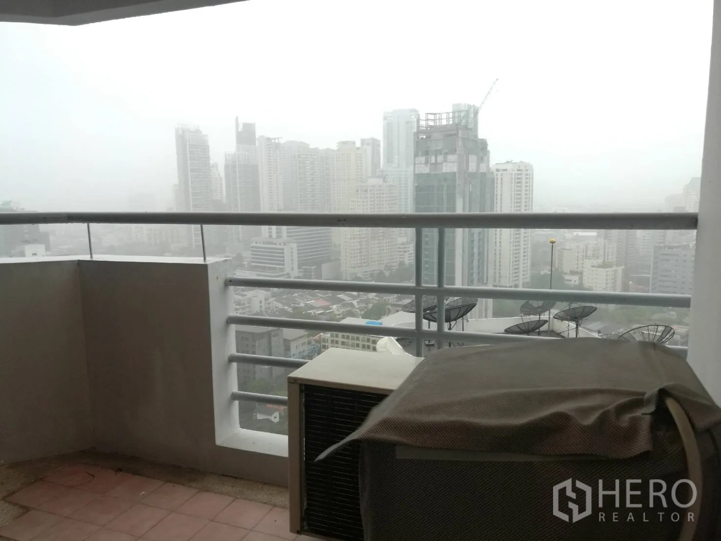 Condominium for rent in Khlong Toei, Bangkok - Covered balcony with safety railing overlooking the Bangkok skyline.