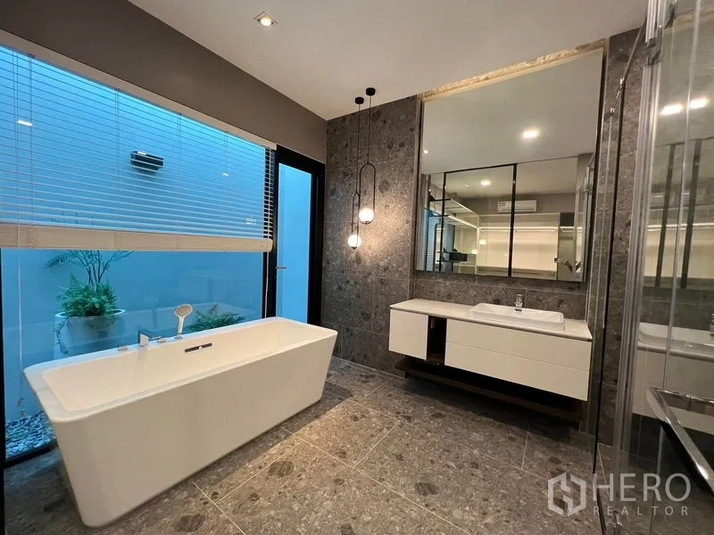 Detached House for sale in Saphan Sung, Bangkok - Luxurious bathroom with freestanding bathtub, stone tiles and a floating vanity.