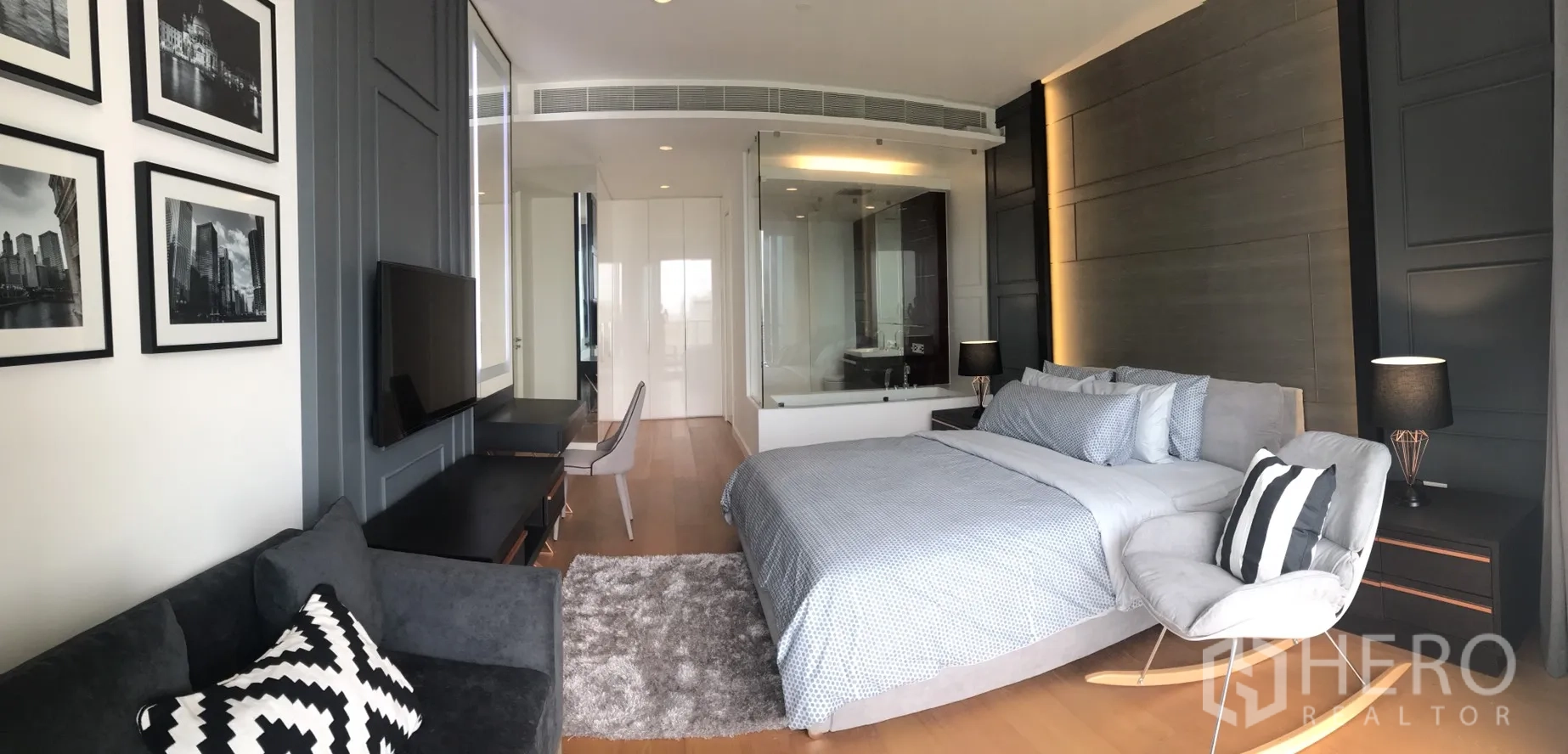 Condominium for rent in Pathum Wan, Bangkok - Master bedroom with glass-walled ensuite bathroom and cozy seating area.