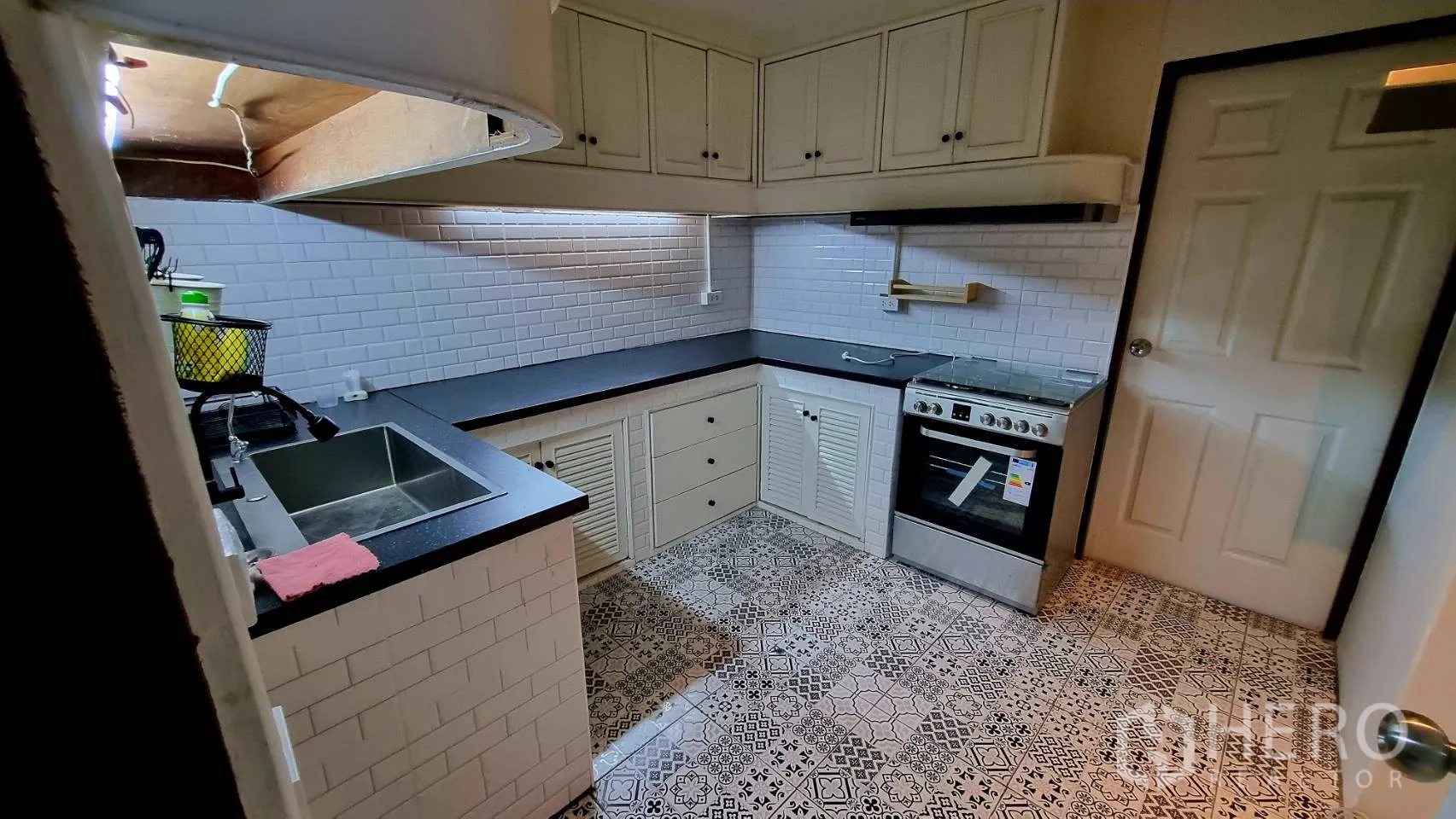Condominium for rent in Watthana, Bangkok - U-shaped kitchen with white subway tiles, patterned floor and gas range.