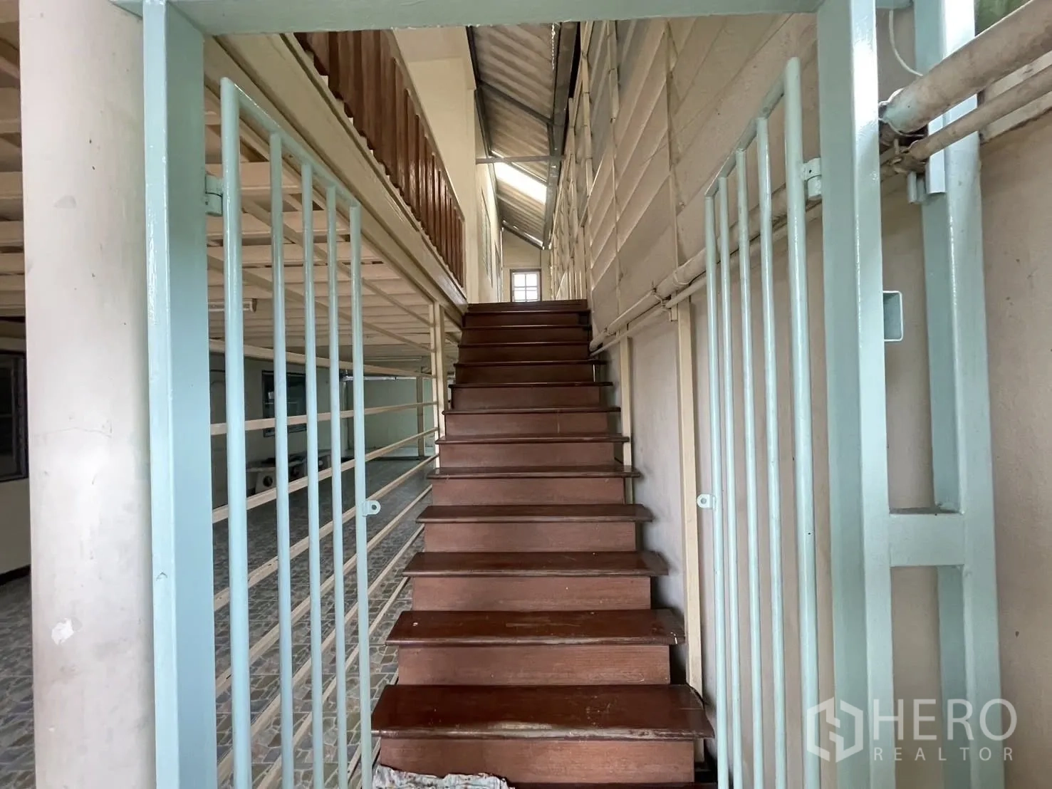 Warehouse for rent in Lat Phrao, Bangkok - Wooden staircase behind security grilles leading to upper level.