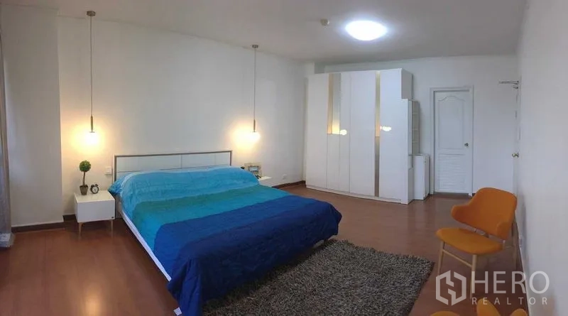 Condominium for rent or sale in Din Daeng, Bangkok - Generous master bedroom with pendant lights, blue bedding, wardrobes and wood flooring.