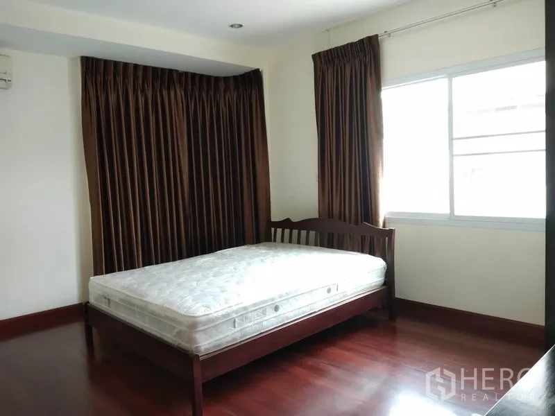 独立式住宅 出租在Watthana, Bangkok - 卧室带木地板、木床与大窗，深色窗帘