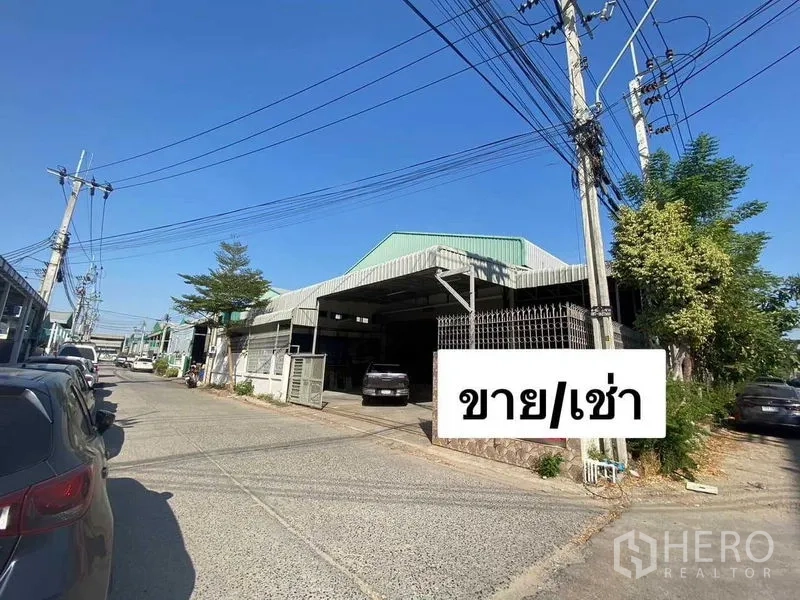คลังสินค้า ให้เช่าหรือขายในMueang Samut Prakan, Samut Prakan - ด้านนอกโกดังติดถนน หลังคาเมทัลชีทสีเขียว ประตูรั้วและพื้นที่จอดรถ