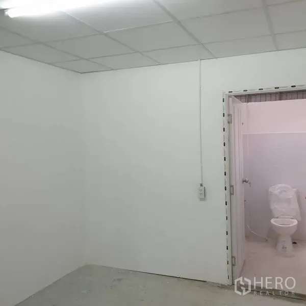 Warehouse for rent in Khlong Toei, Bangkok - White office room with drop ceiling and doorway leading to restroom.