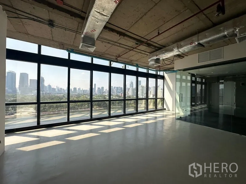 办公空间 出租在Watthana, Bangkok - 转角区域配全景落地窗与玻璃会议室，自然光充足，俯瞰城市景观。