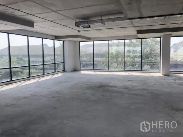 办公空间 出租在Suan Luang, Bangkok - 转角工作区，落地窗俯瞰绿意与周边屋顶景观。
