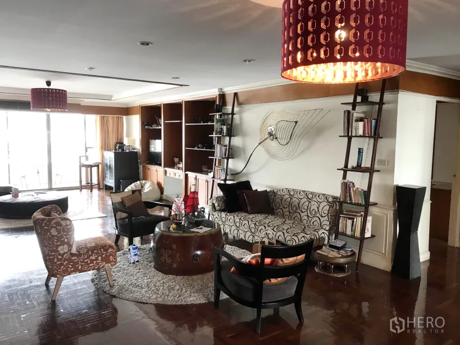 คอนโด ให้เช่าในWatthana, Bangkok - ห้องนั่งเล่นกว้าง พื้นไม้ขัดเงา ชั้นวางบิลท์อิน ผนังตกแต่ง และประตูกระจกบานเลื่อนไปยังระเบียงที่สว่าง