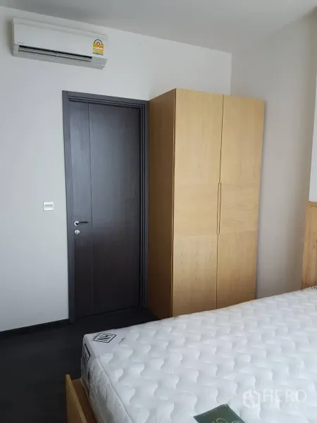 公寓 出租或出售在Watthana, Bangkok - 卧室一角，木质衣柜、空调与白色床垫。