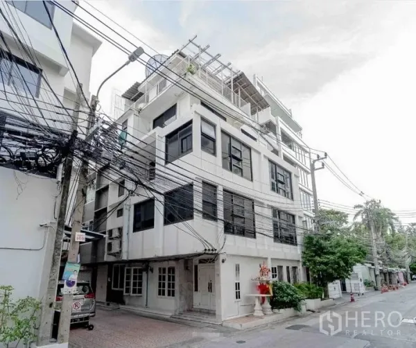 带办公室的家 出租在Bang Rak, Bangkok - 安静小巷中的白色多层商住两用楼，黑色窗框并设屋顶露台的转角外观。